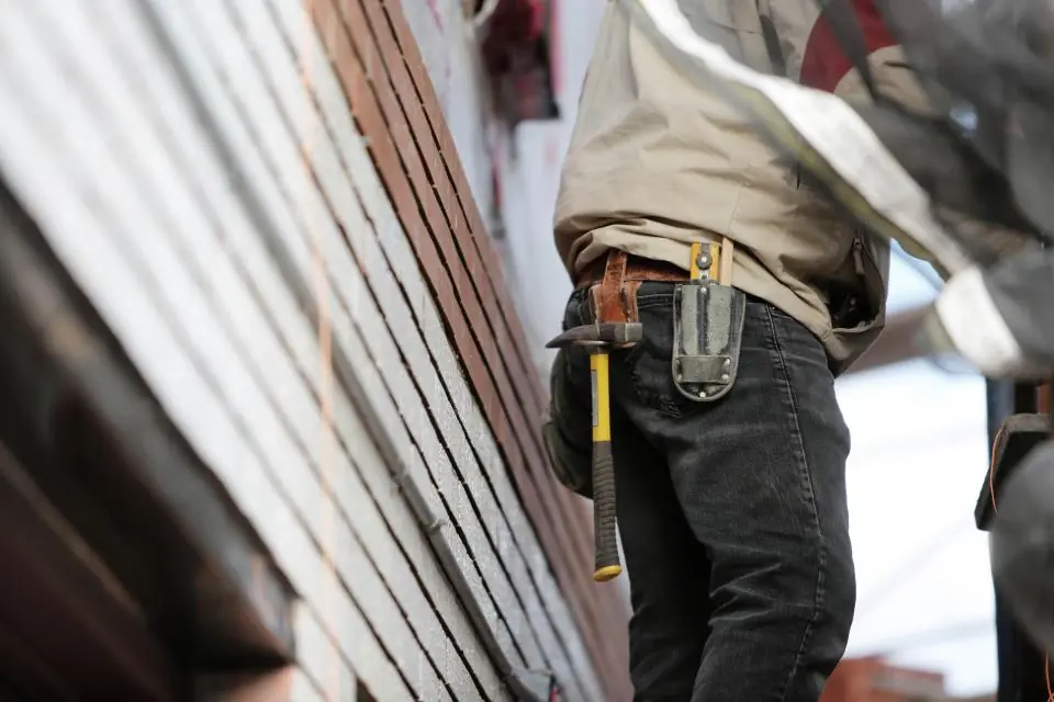 Handyman with a tool belt working on siding